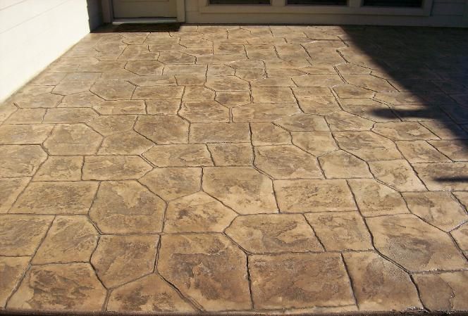 A patio with a brick pattern and a door in the background