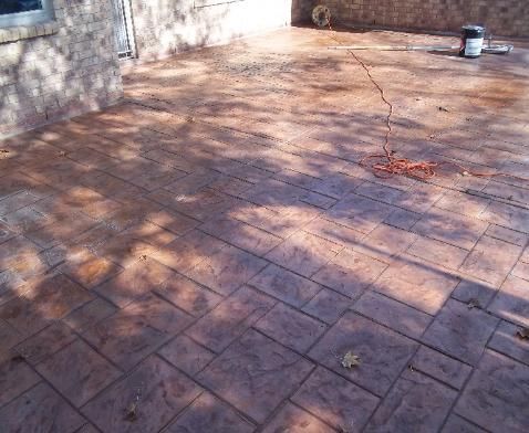 A brick patio with a bucket of paint in the background