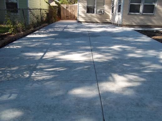 A concrete driveway with a house in the background