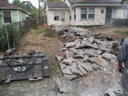 A man is standing next to a pile of rocks in front of a house.