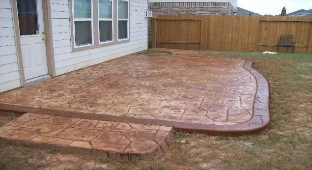 A concrete patio with steps and a wooden fence in front of a house.