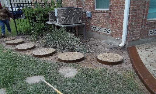 A man is standing in the grass in front of a brick house.