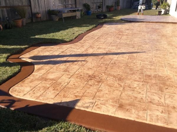 A concrete patio with a brown border in a backyard