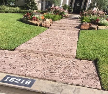 A concrete walkway leading to the front door of a house.