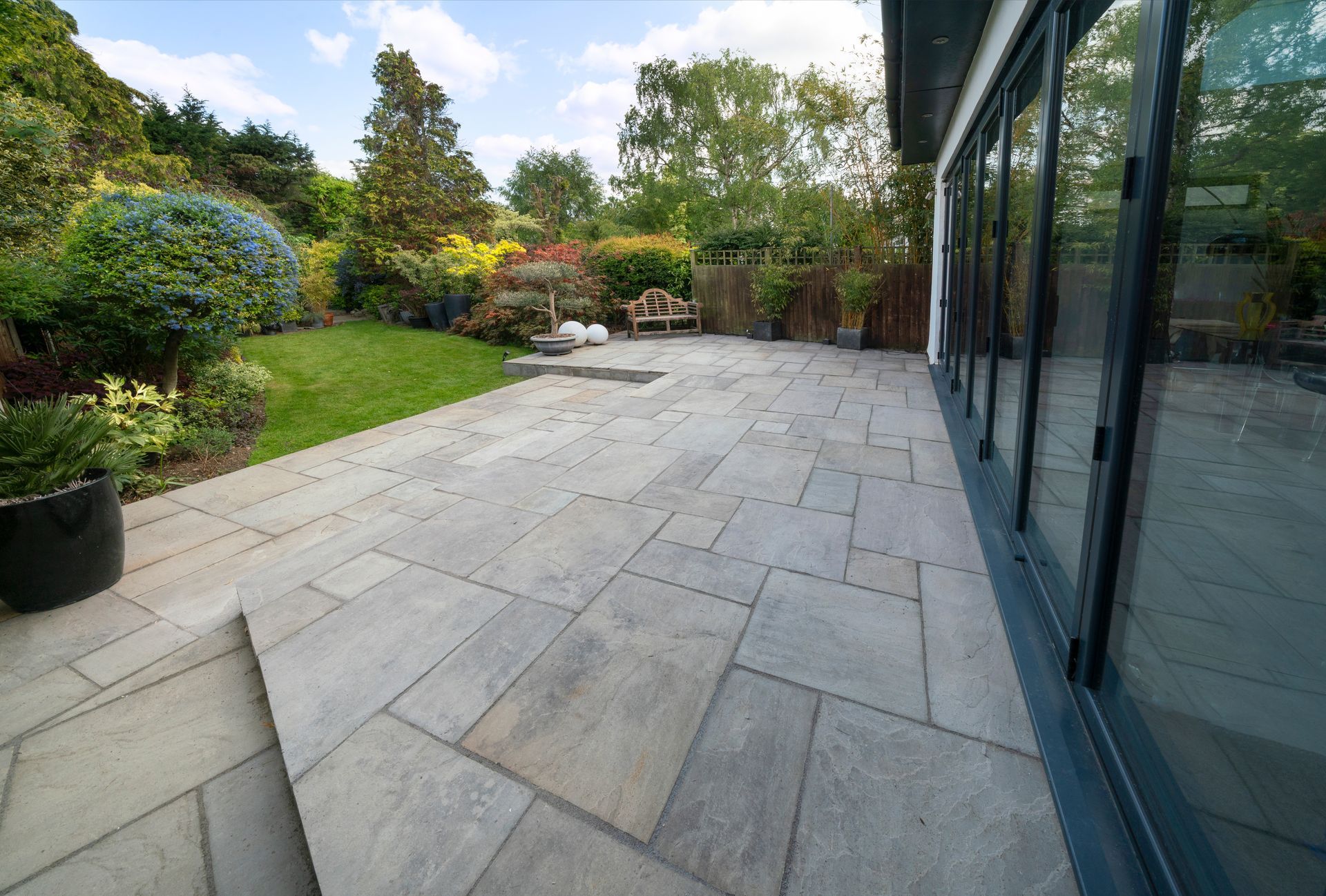 A large patio with a bench in the backyard of a house.