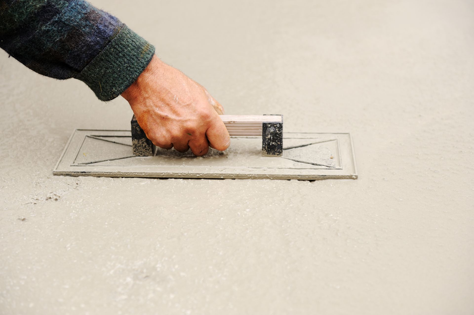 A person is using a trowel on a concrete surface.