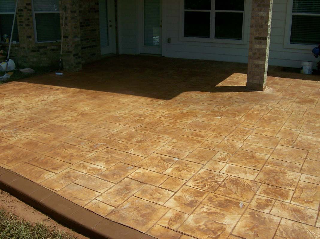 A concrete patio with a brick wall in the background