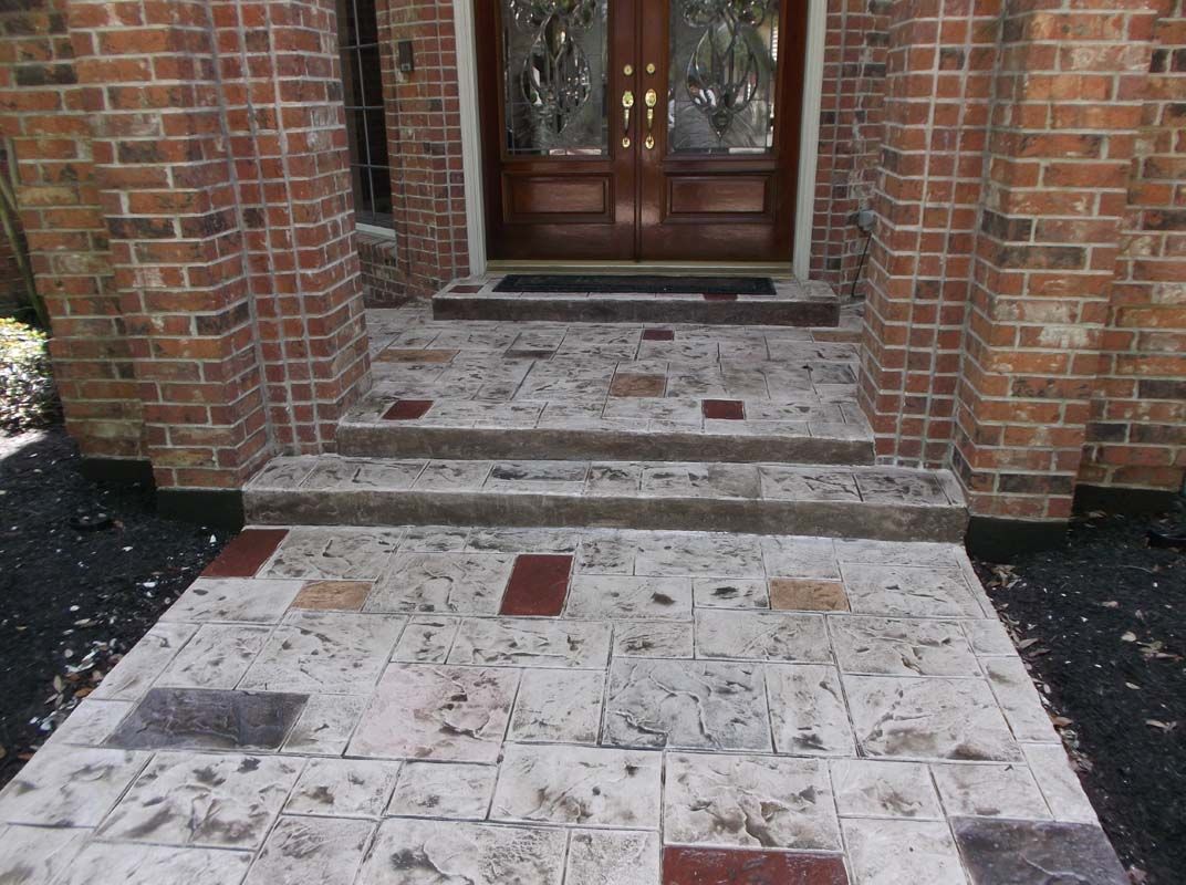 A brick house with a concrete walkway leading to the front door