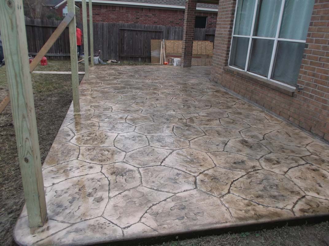 A patio with a wooden fence and a brick building in the background.