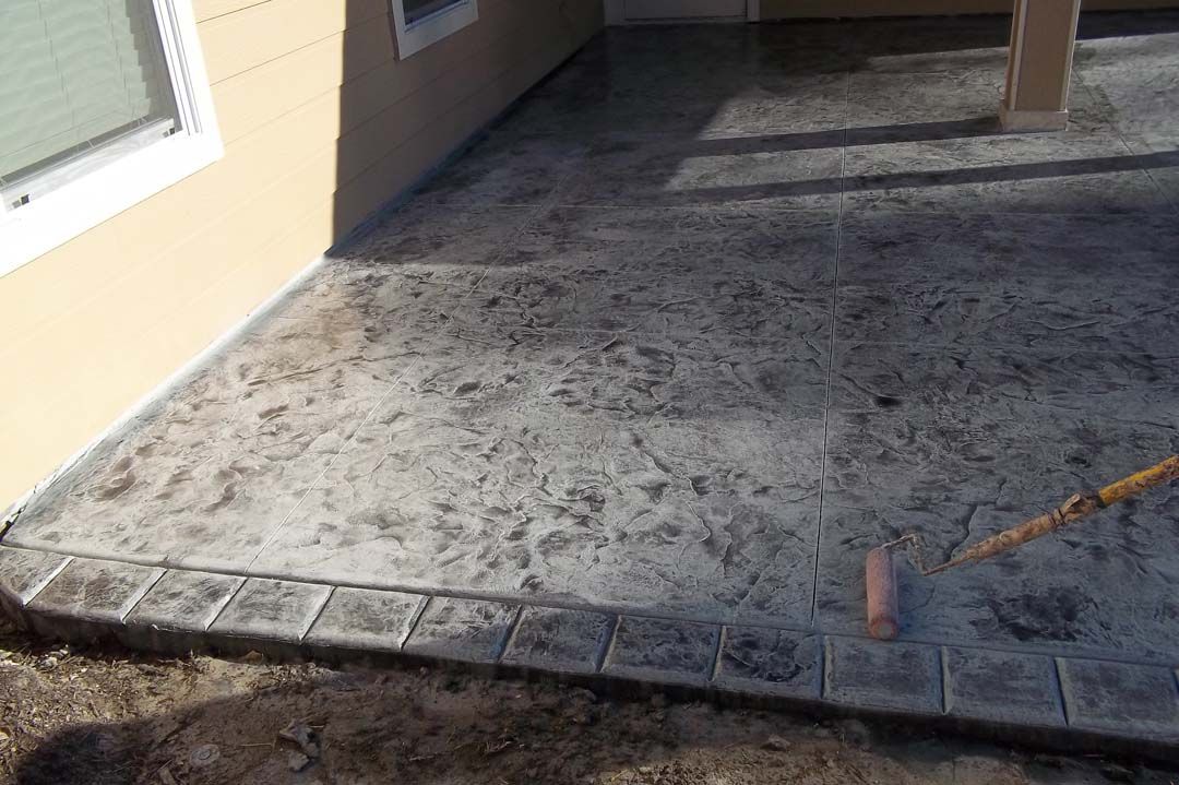 A concrete patio is being built in front of a house.