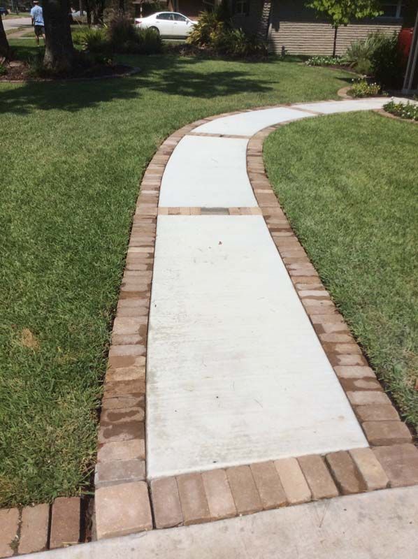A brick and concrete walkway leading to a house