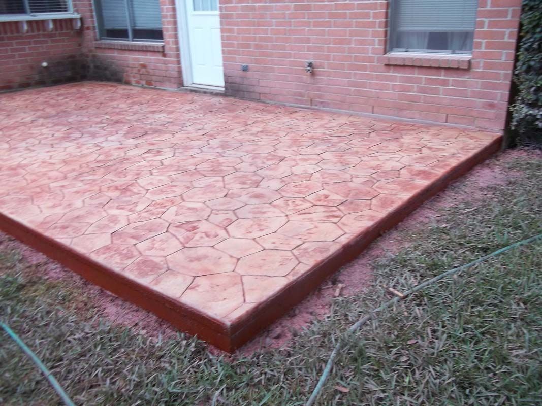 A brick house with a concrete patio in front of it.