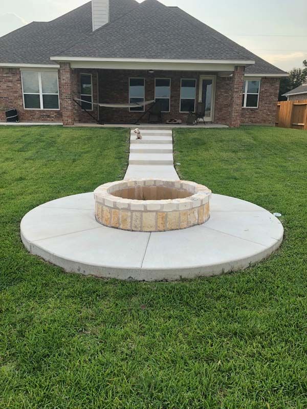 There is a fire pit in the middle of the grass in front of a house.