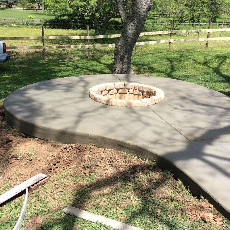 A concrete patio with a fire pit in the middle