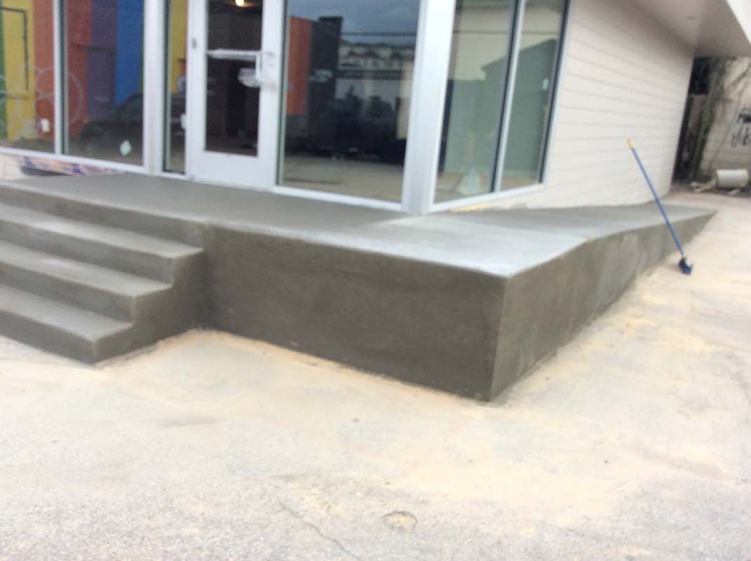 A concrete walkway with stairs leading up to a building.