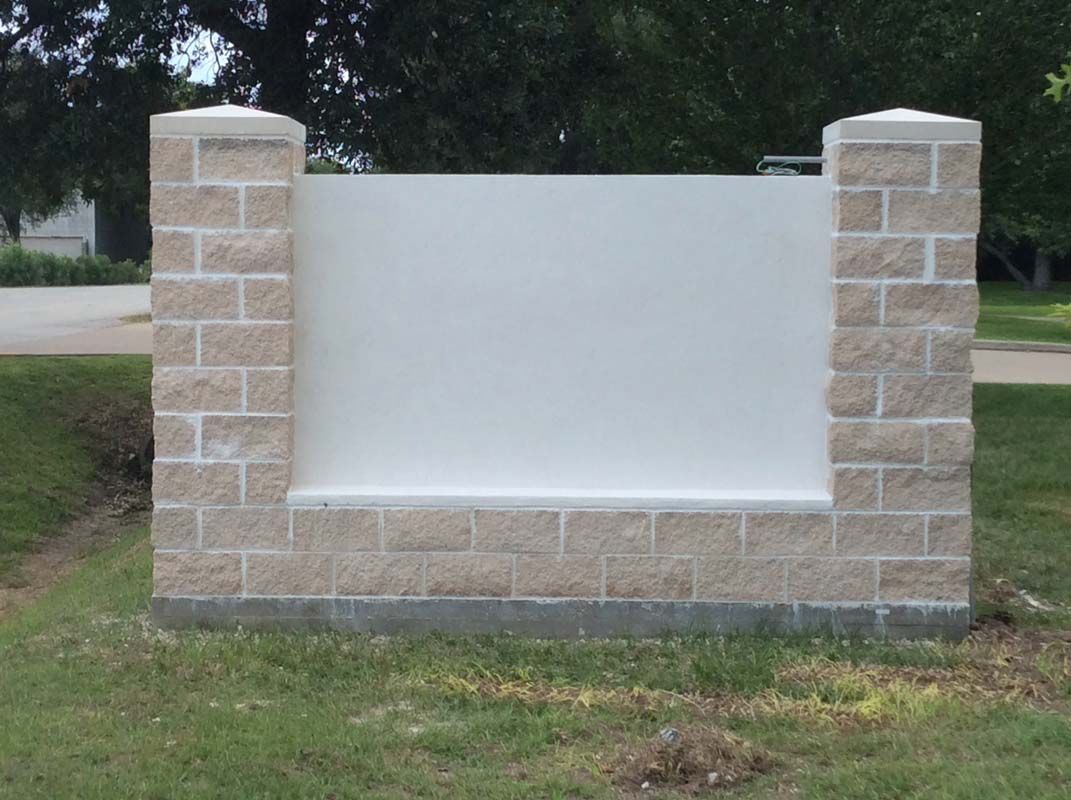 A white sign is sitting on top of a brick wall.