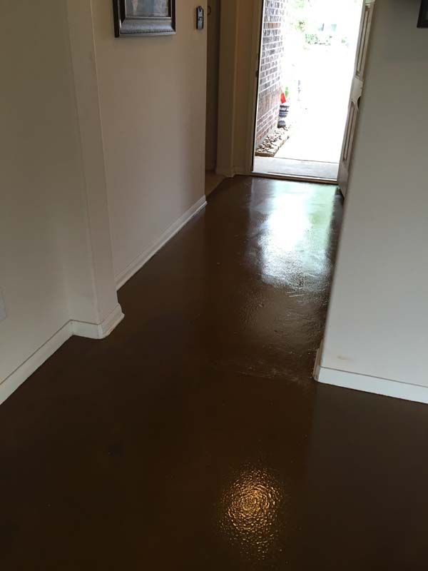 A hallway with a brown floor and white walls leading to a door.