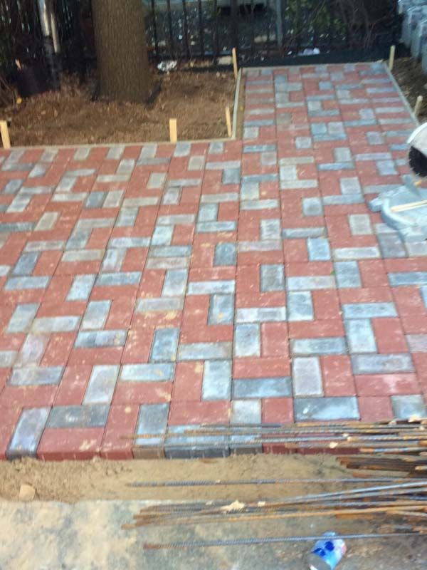 A brick walkway is being built in a backyard.