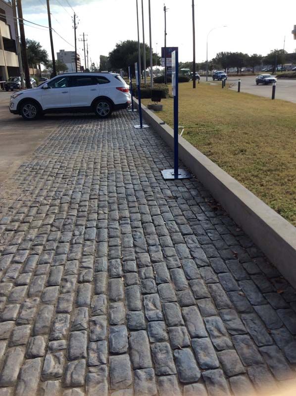 A white suv is parked on a cobblestone driveway