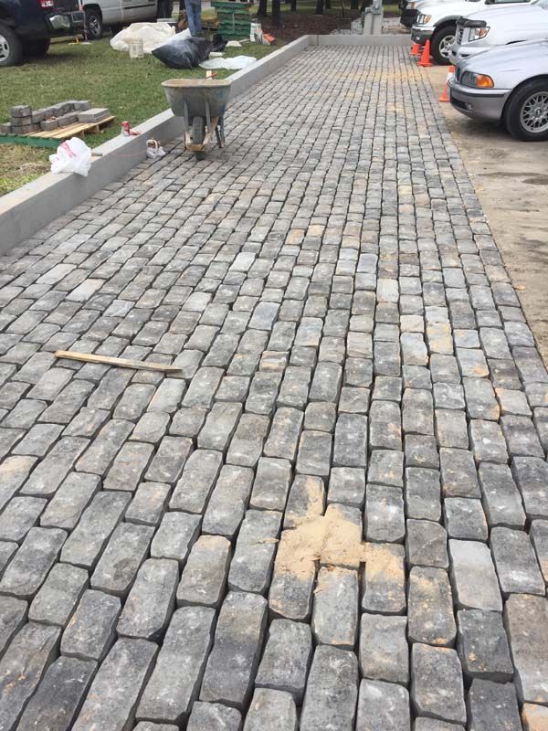 A brick walkway is being built in a parking lot.