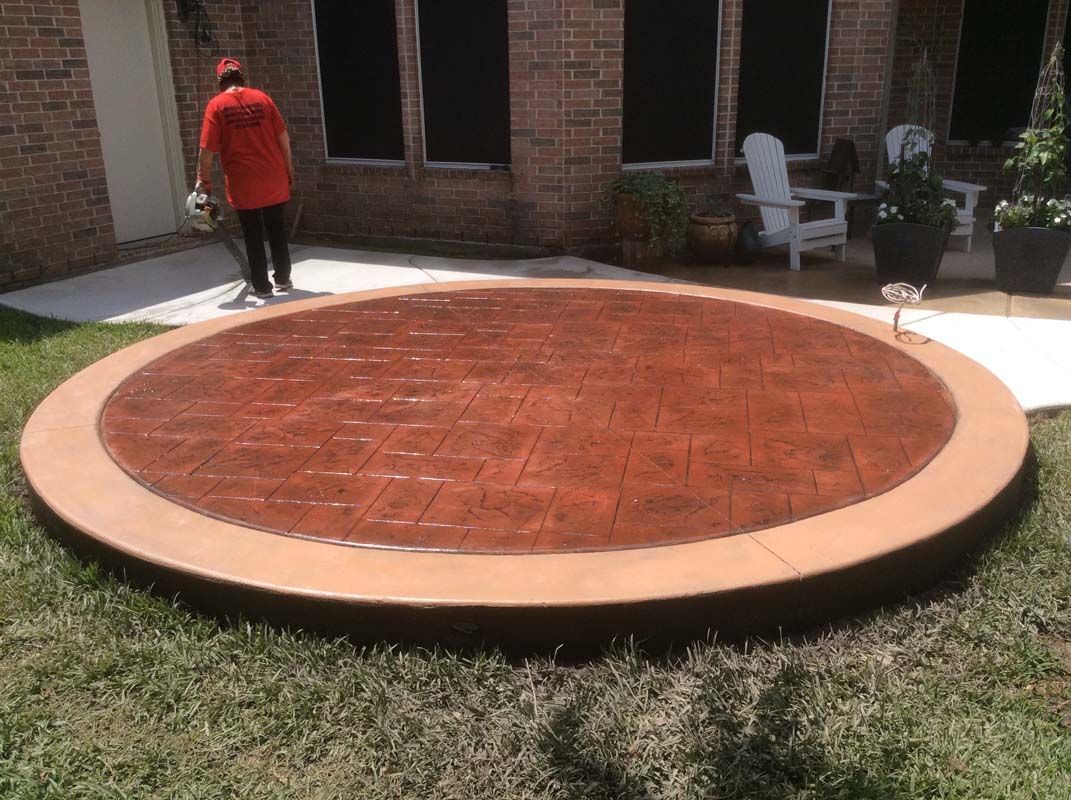 A man in a red shirt is standing on a circular concrete patio.