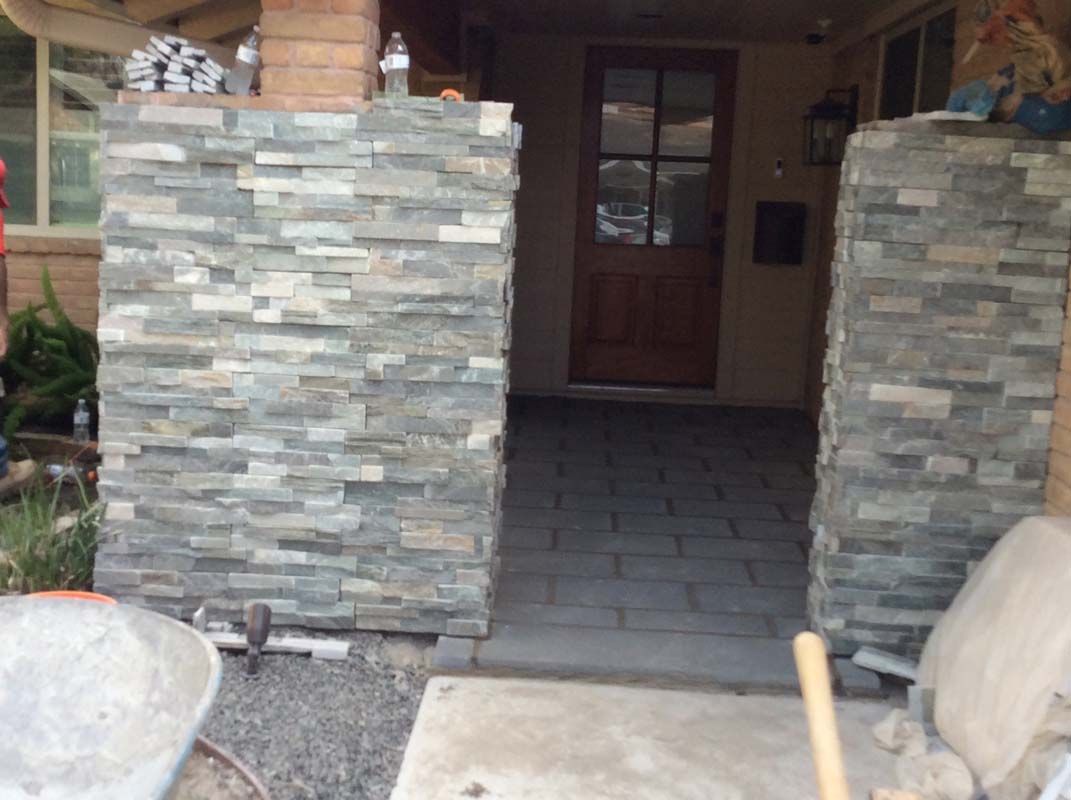 A stone wall is being built in front of a house