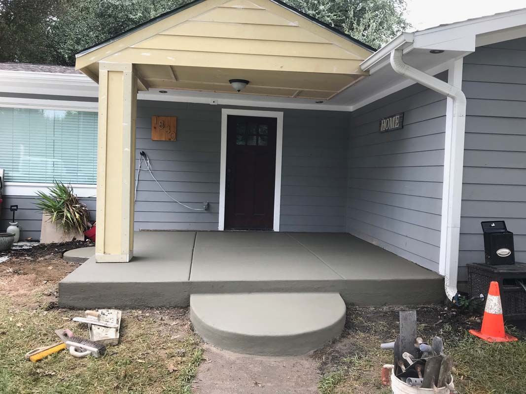 A concrete porch is being built in front of a house.