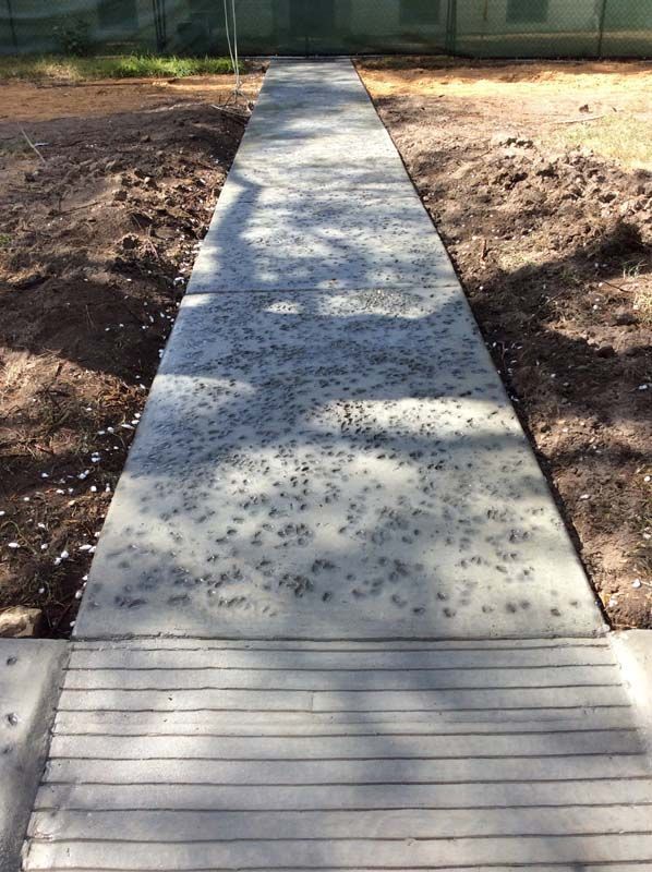 A concrete walkway going through a dirt field.