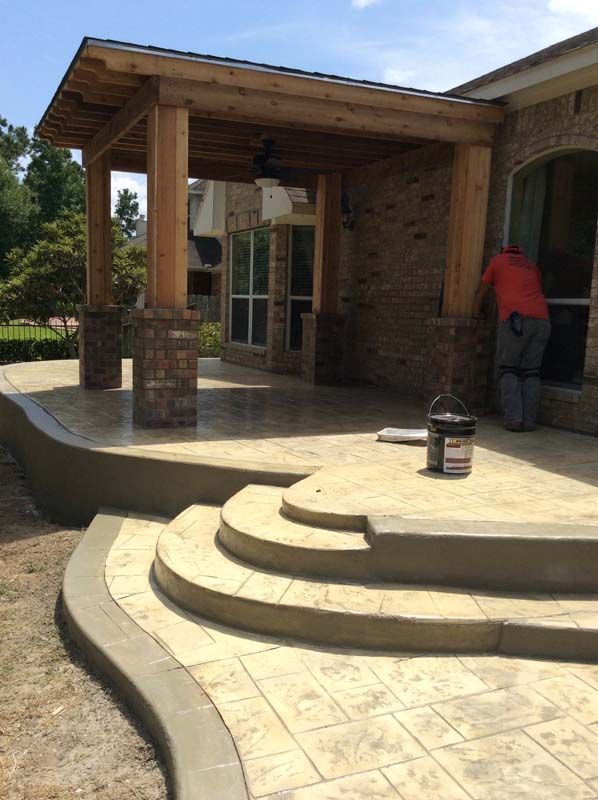 A man is working on a patio in front of a house.