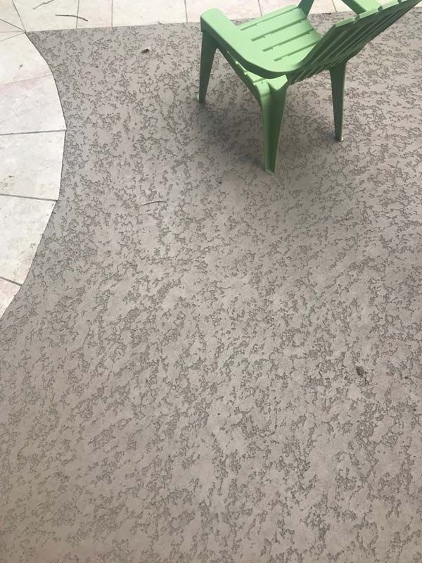 A green chair is sitting on top of a concrete patio.