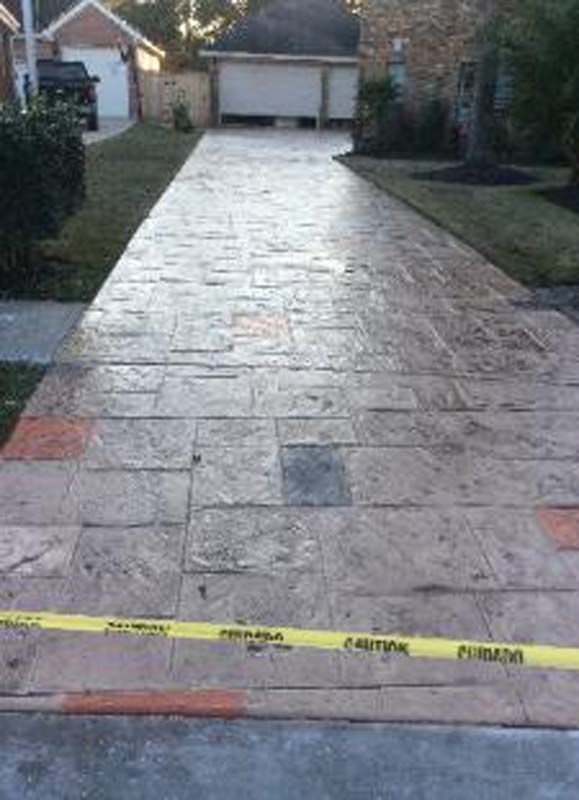 A concrete driveway in front of a house with a yellow tape.