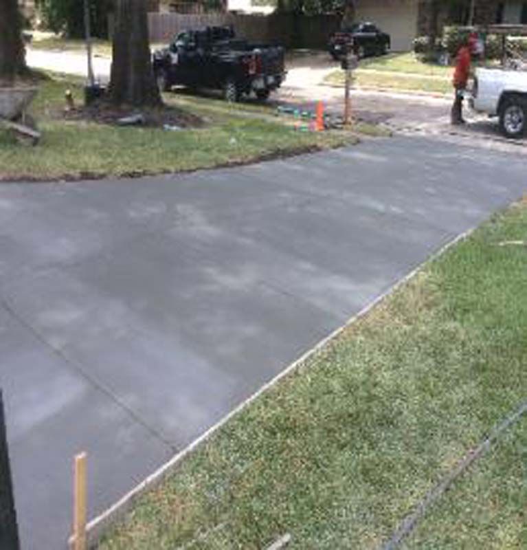 A concrete driveway is being built in front of a house.