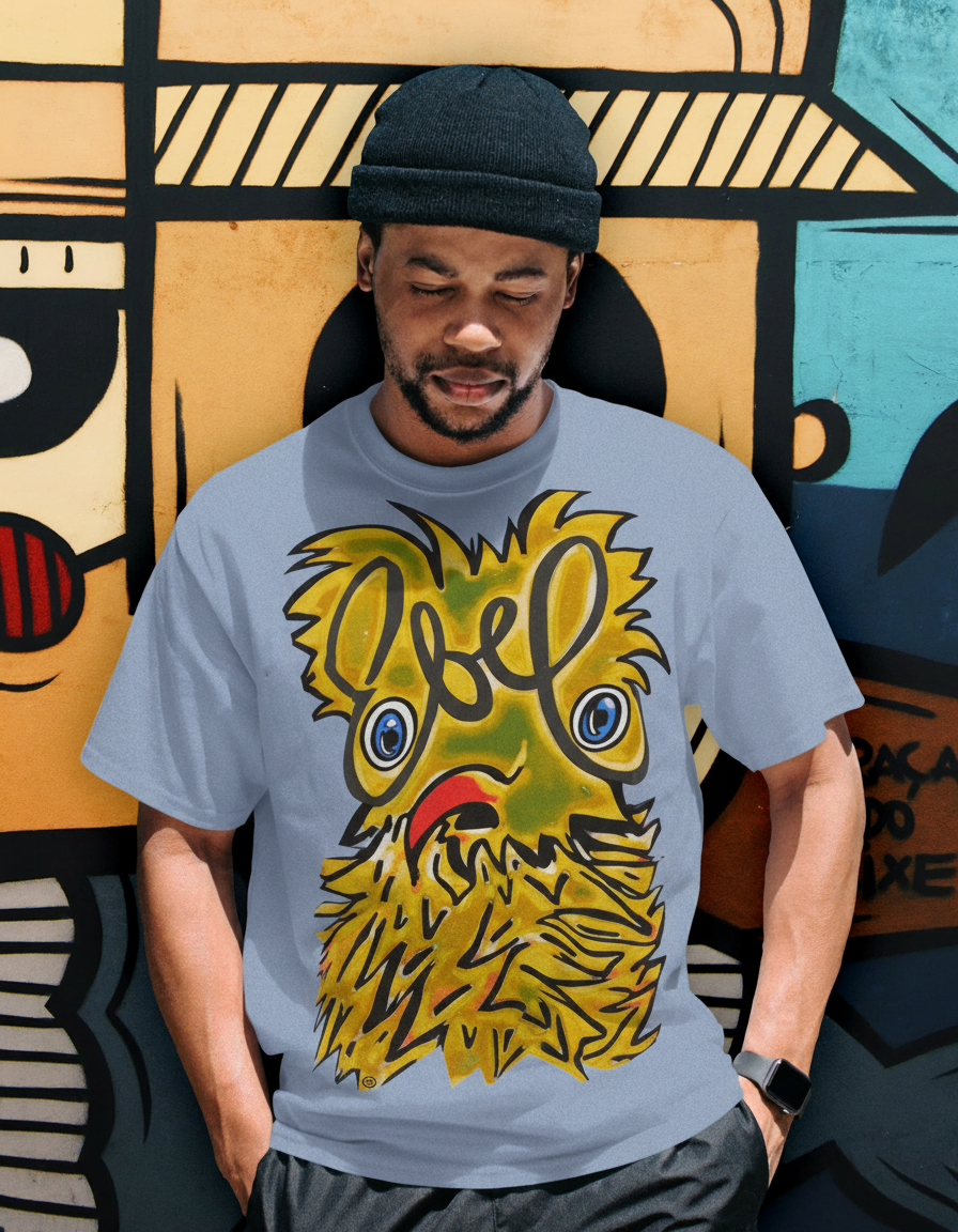 Man in white t-shirt with art on it, wearing black beanie, leaning against graffiti-covered wall.