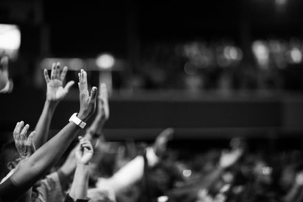 A crowd of people are raising their hands in the air at a concert.