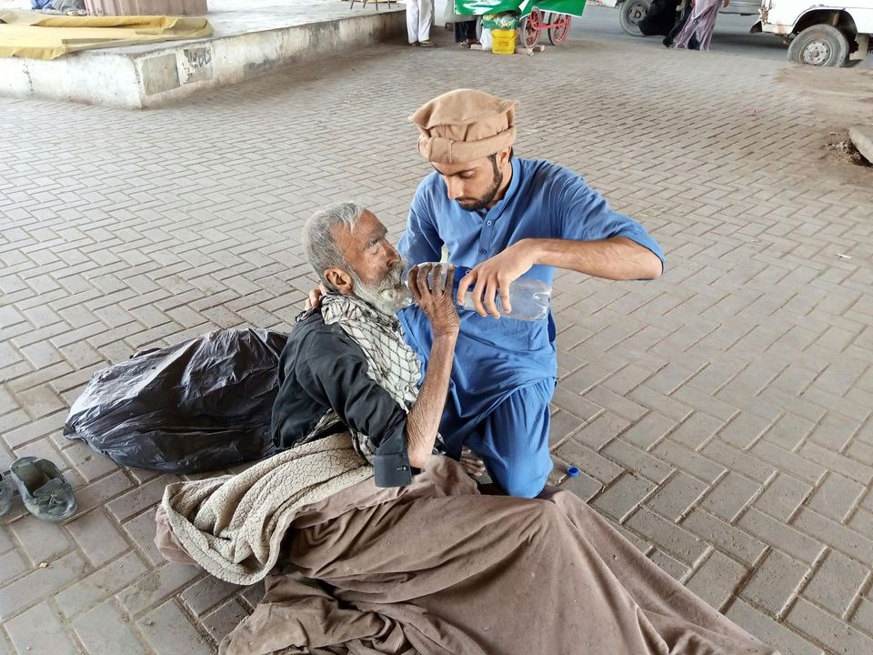 A man is kneeling down next to a man laying on the ground.