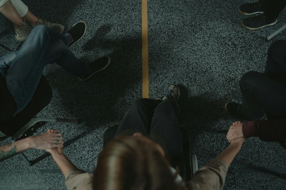 A group of people are sitting in a circle on the floor holding hands.