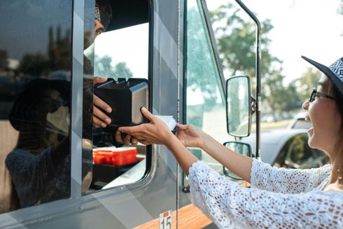 A woman is getting food from a food truck.
