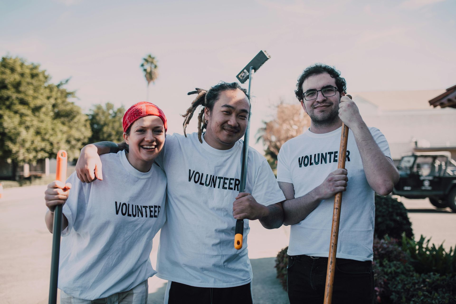 Three volunteers are posing for a picture while holding shovels.