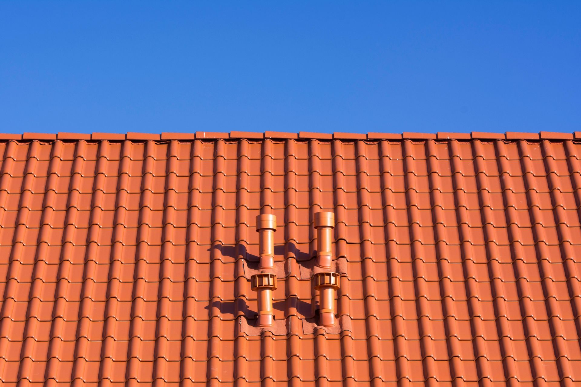 A red tiled roof with a blue sky in the background