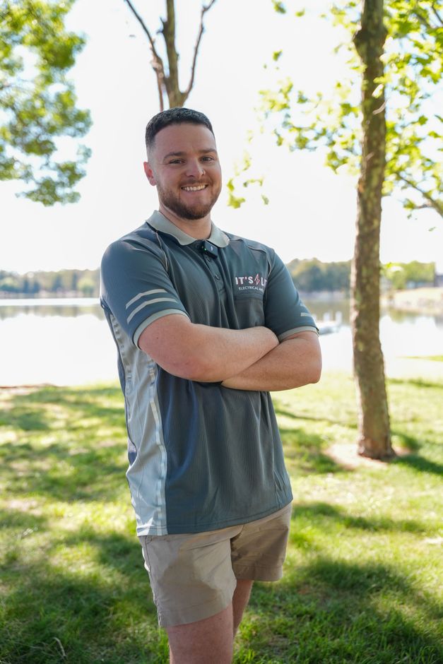 Electrician working on wires on ladder and at a panel, both wearing safety gear.