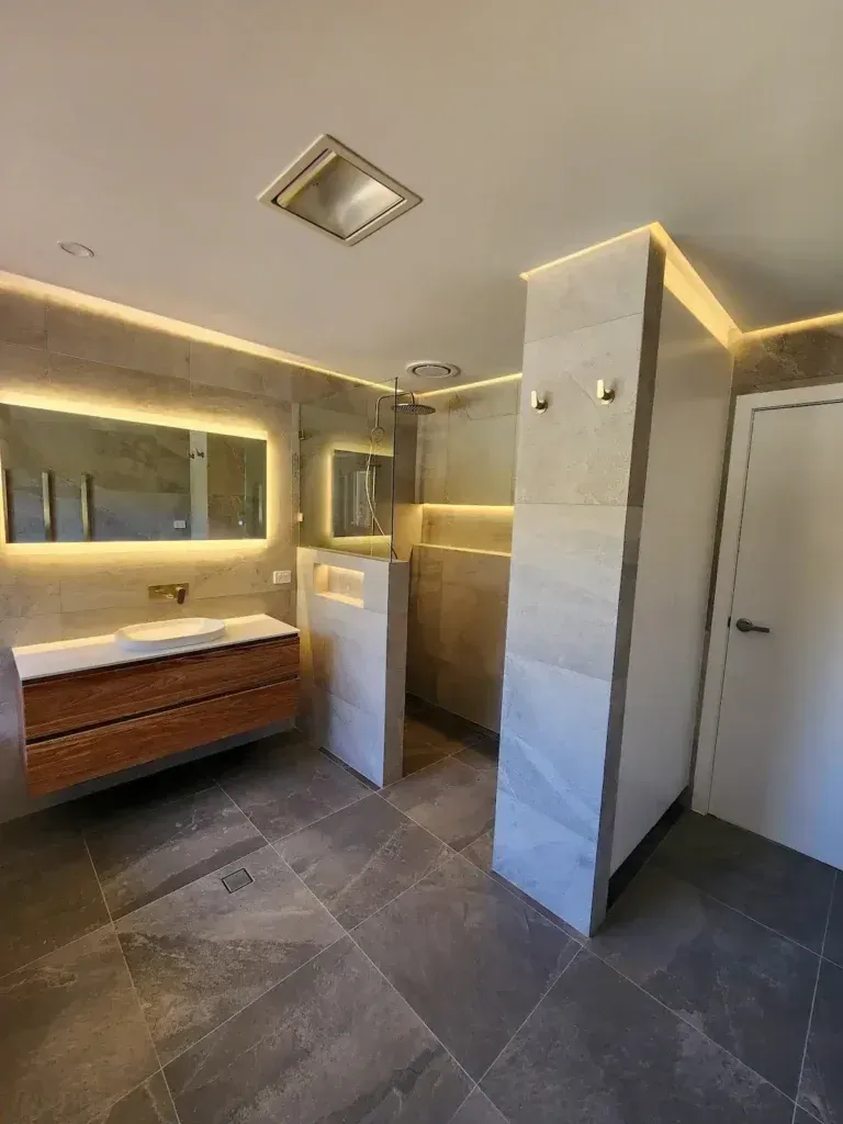 Modern bathroom with a wooden vanity, gray tile, and a walk-in shower.
