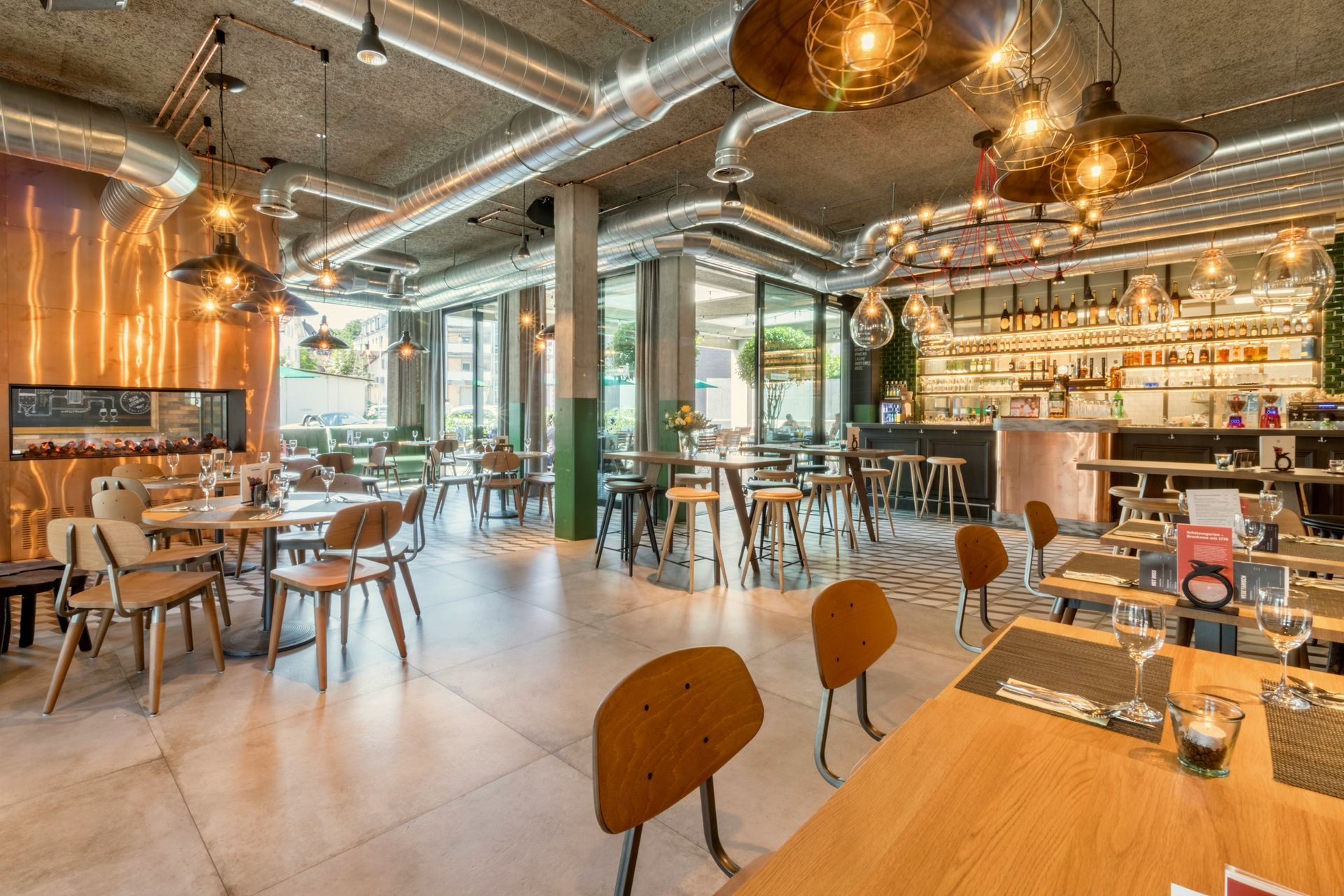 An interior shot of a modern, industrial-style restaurant with warm lighting, wooden tables, and metal accents.