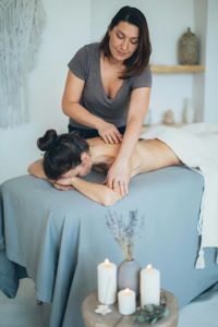 Massage therapist working on a client on a treatment table with candles nearby