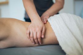 Hands massaging a person’s back beside a white towel in a spa setting