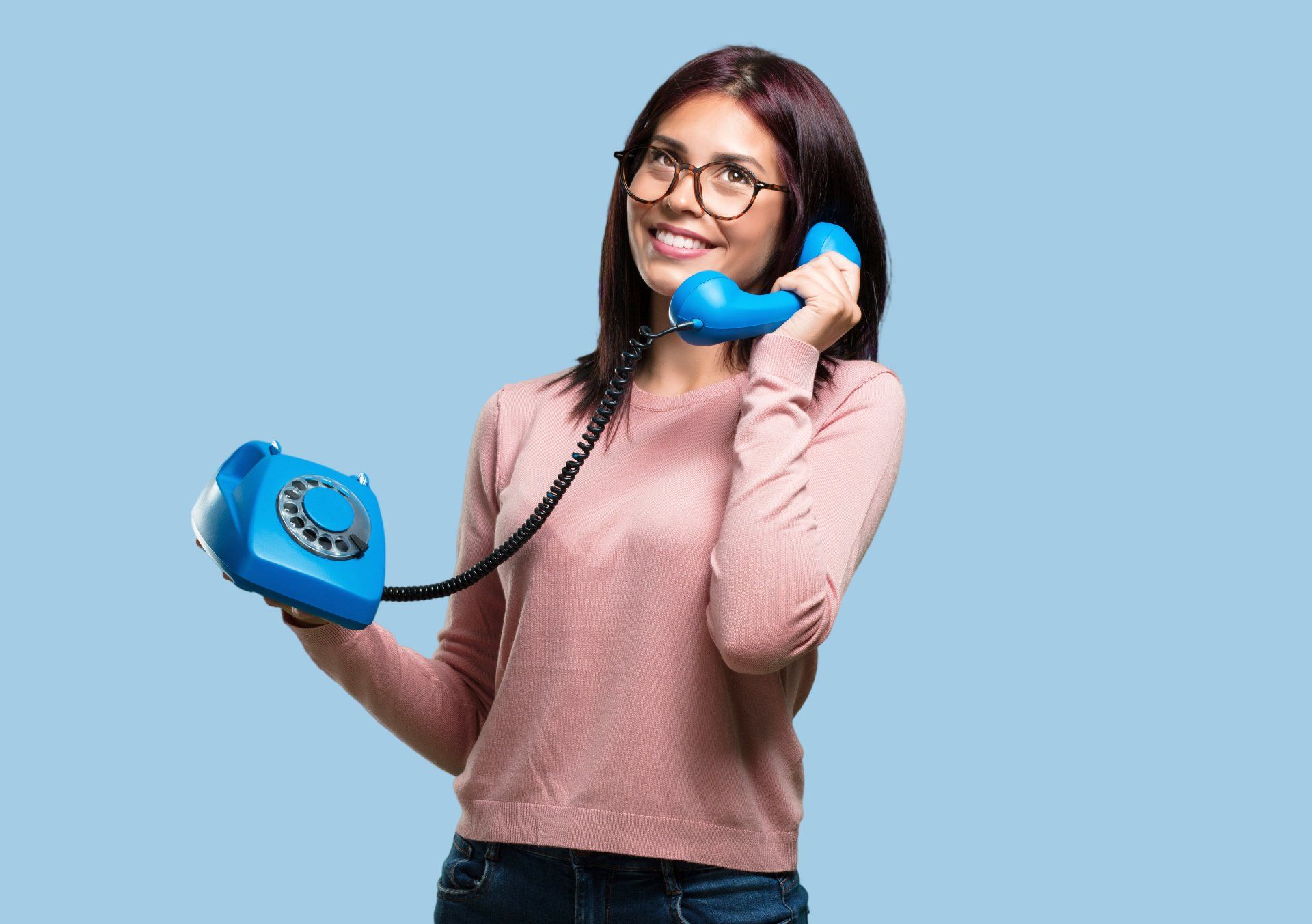 A woman is talking on a blue telephone.