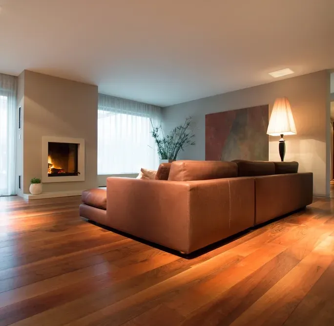 Modern living room with a brown leather sofa, fireplace, and hardwood floors — Proshield Insulation & Waterproofing In Shellharbour, NSW
