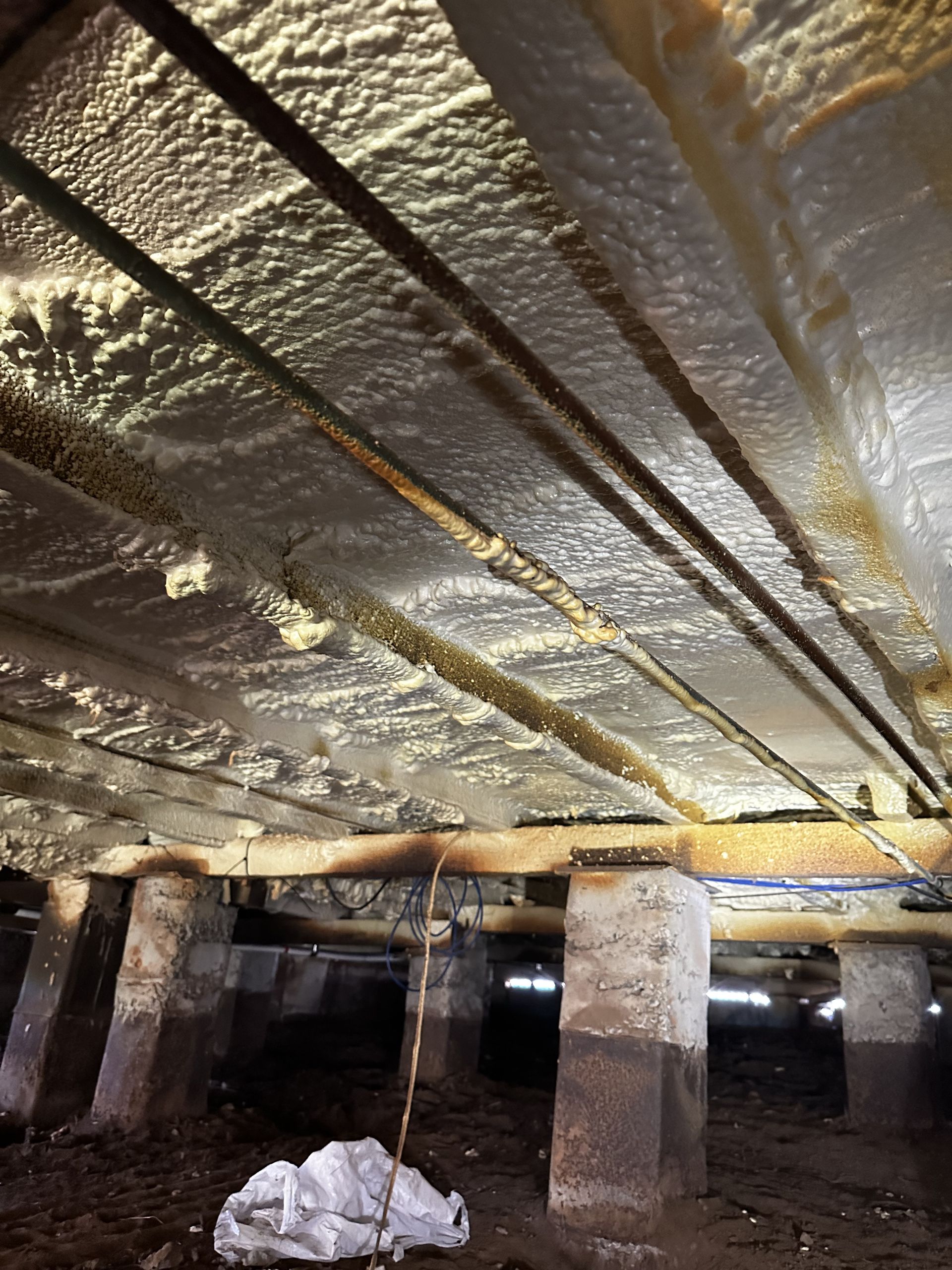 Underneath a house, insulation attached to floor joists. Exposed beams and support pillars — Proshield Insulation & Waterproofing In Shell Cove, NSW