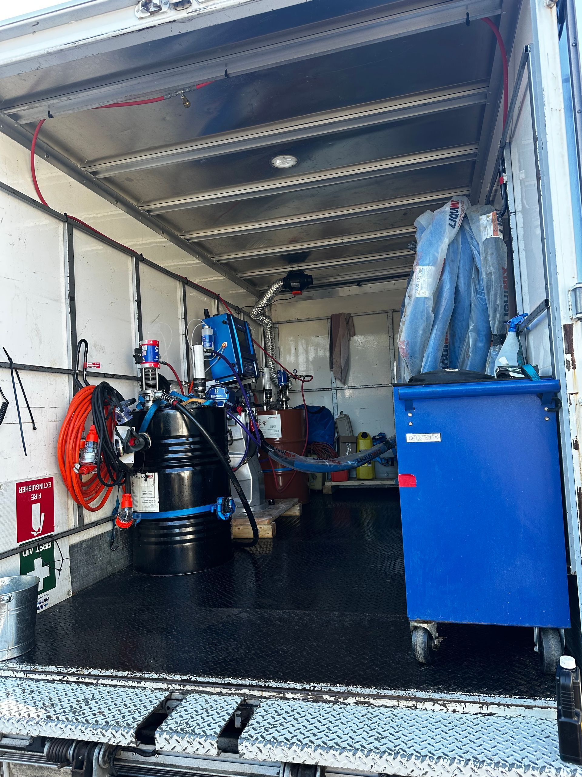 Interior of a service truck with equipment. Black drums, blue cabinets, hoses, and tools are visible  — Proshield Insulation & Waterproofing In Shell Cove, NSW