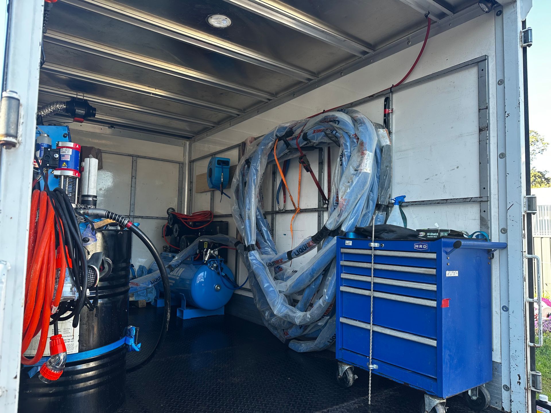 Inside of a truck filled with equipment. Tools, hoses, and a blue toolbox are visible — Proshield Insulation & Waterproofing In Shellharbour, NSW