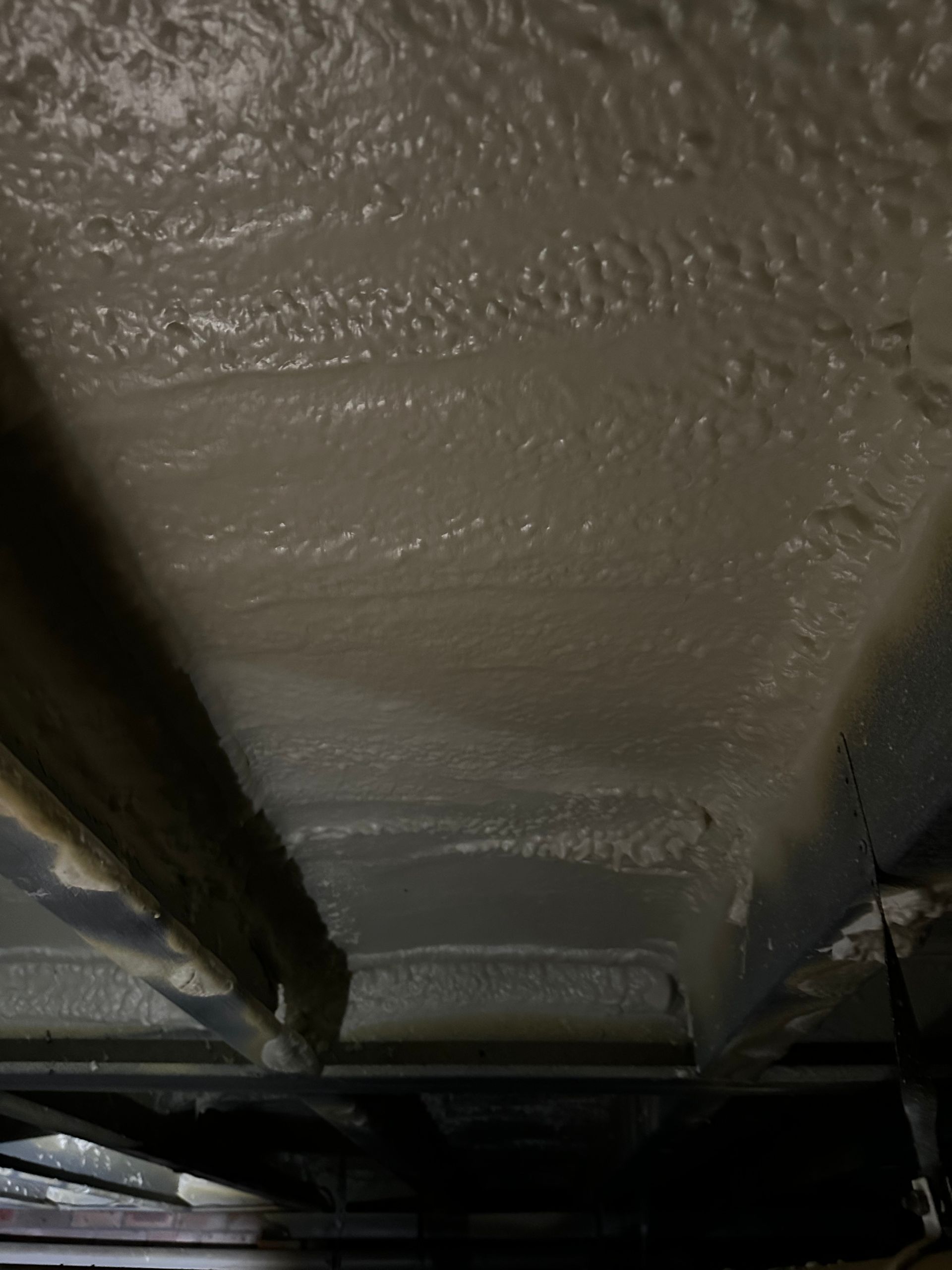 Spray foam insulation on the underside of a floor, viewed from below; light gray color   — Proshield Insulation & Waterproofing In Shell Cove, NSW